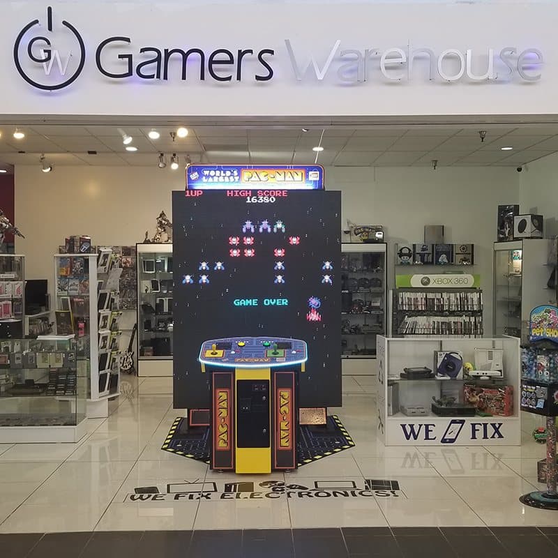 Gamers Warehouse storefront in Tucson Mall, with the World's Largest Pac-Man arcade and a We Fix sign for phone and electronics repair
